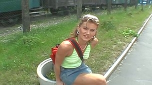 Blond showcases boobs off behind a railroad car
